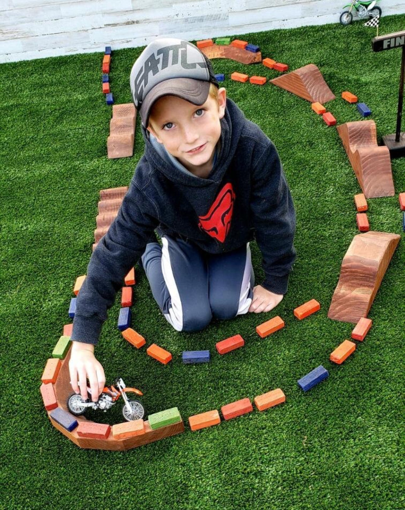 boy playing with dirtbikes in the dirt, wearing dirtblike apparel and hats
