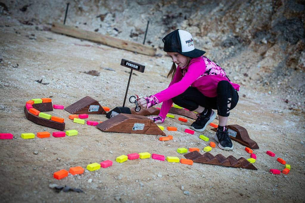 happy toddler girl playing with dirt bike, playing at dirt bike track, truck, wooden track, neon blocks