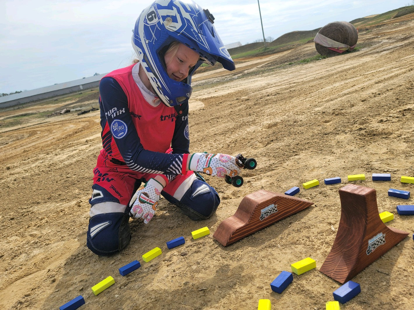 happy girl with toy wooden track with big monster track and monster trucks jumping