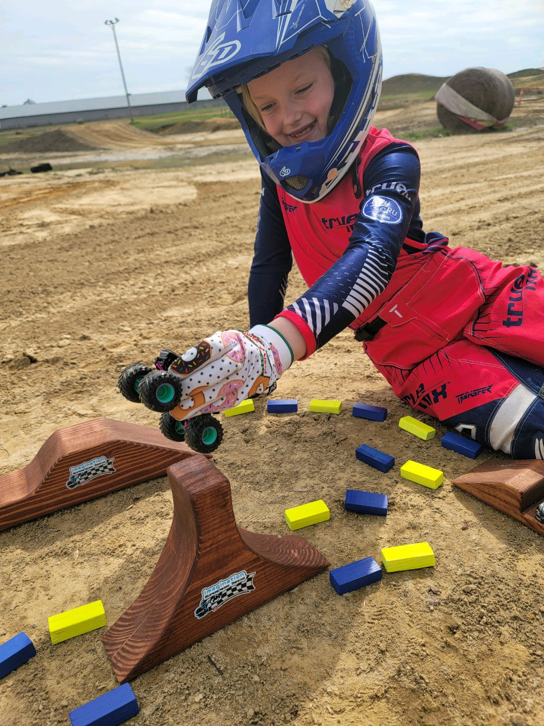 happy girl with toy wooden track with big monster track and monster trucks jumping