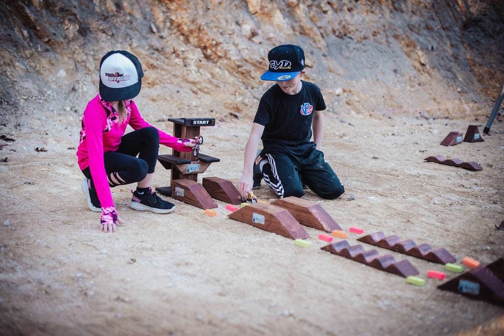 boy and girl playing with dirtbikes in the dirt, wearing dirtblike apparel and hats